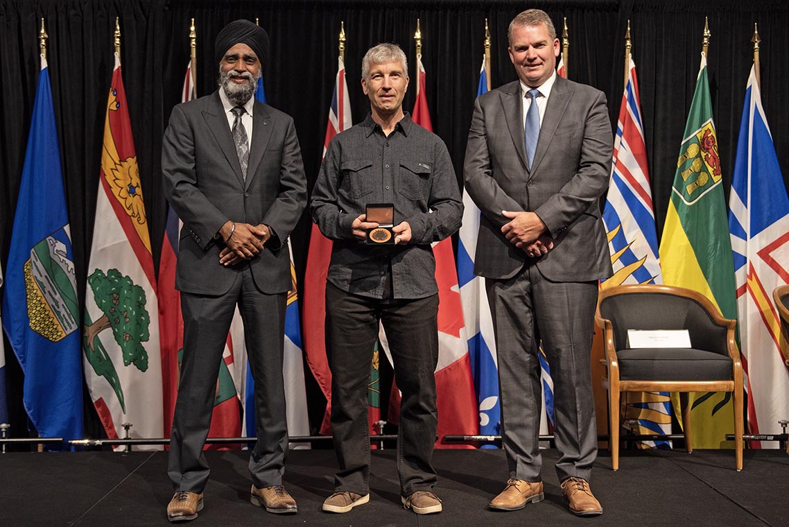 The Honourable Harjit S. Sajjan, President of the King’s Privy Council for Canada and Minister of  Emergency Preparedness (far left) and Minister responsible for the Pacific Economic  Development Agency of Canada, and the Honourable Bloyce Thompson, Deputy  Premier, Minister of Justice and Public Safety and Attorney General for Prince  Edward Island (far right) are pictured with the 2022 award recipient of the  Emergency Management Exemplary Service Award for the Search and Rescue Volunteers  category.